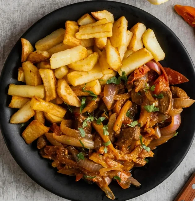 A side dish plate featuring golden crispy fries paired with a flavorful vegetable and meat stir-fry, garnished with fresh herbs, served on a black plate.