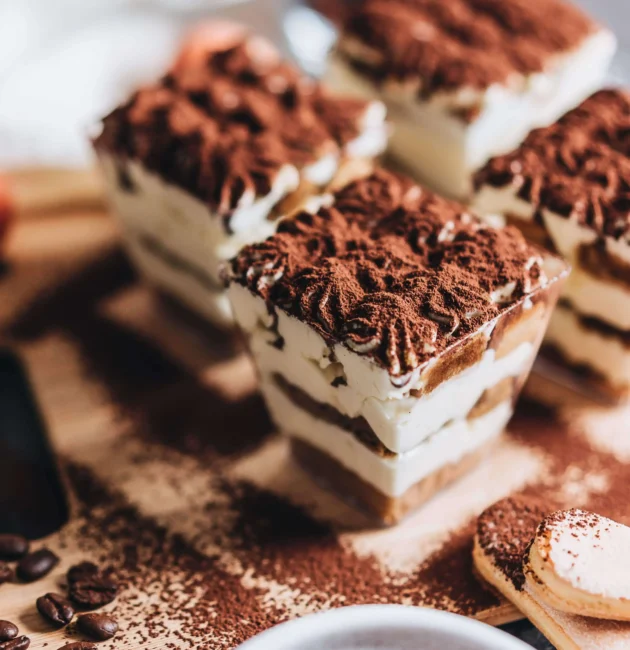 A close-up view of a decadent chocolate cake with a smooth, glossy ganache topping and a sprinkle of powdered sugar