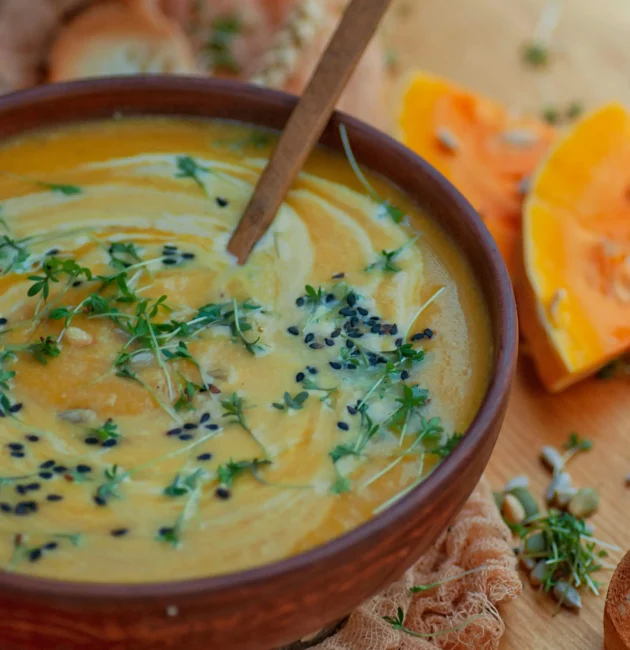 A close-up of a bowl of hearty soup, garnished with fresh herbs and served with a side of bread, showcasing warm and comforting flavors.